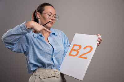 woman pointing at empty canvas and brush on gray background